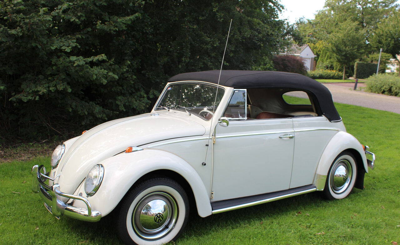 Kever cabrio 1963 met gesloten zwart dak, schuin van voren op het gras.