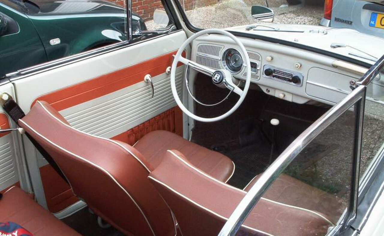Interieur van de Kever cabrio met groot stuurwiel, eenvoudig dashboard en roodbruine leren stoelen.